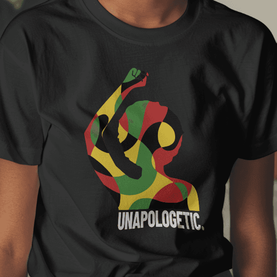 Person wearing a black t-shirt with a colorful design and text in a room with plants and furniture.