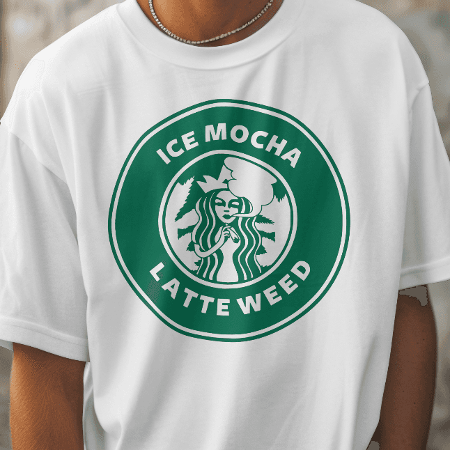 Person wearing a white t-shirt with a green logo and text, standing against a textured wall.