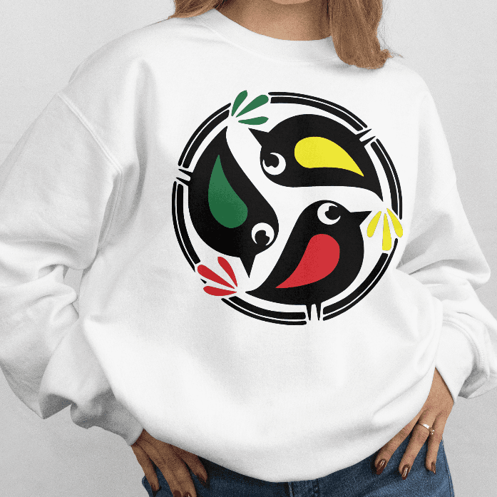 Person wearing a white sweatshirt with 3 birds in a colorful rasta inspirded design on a plain background