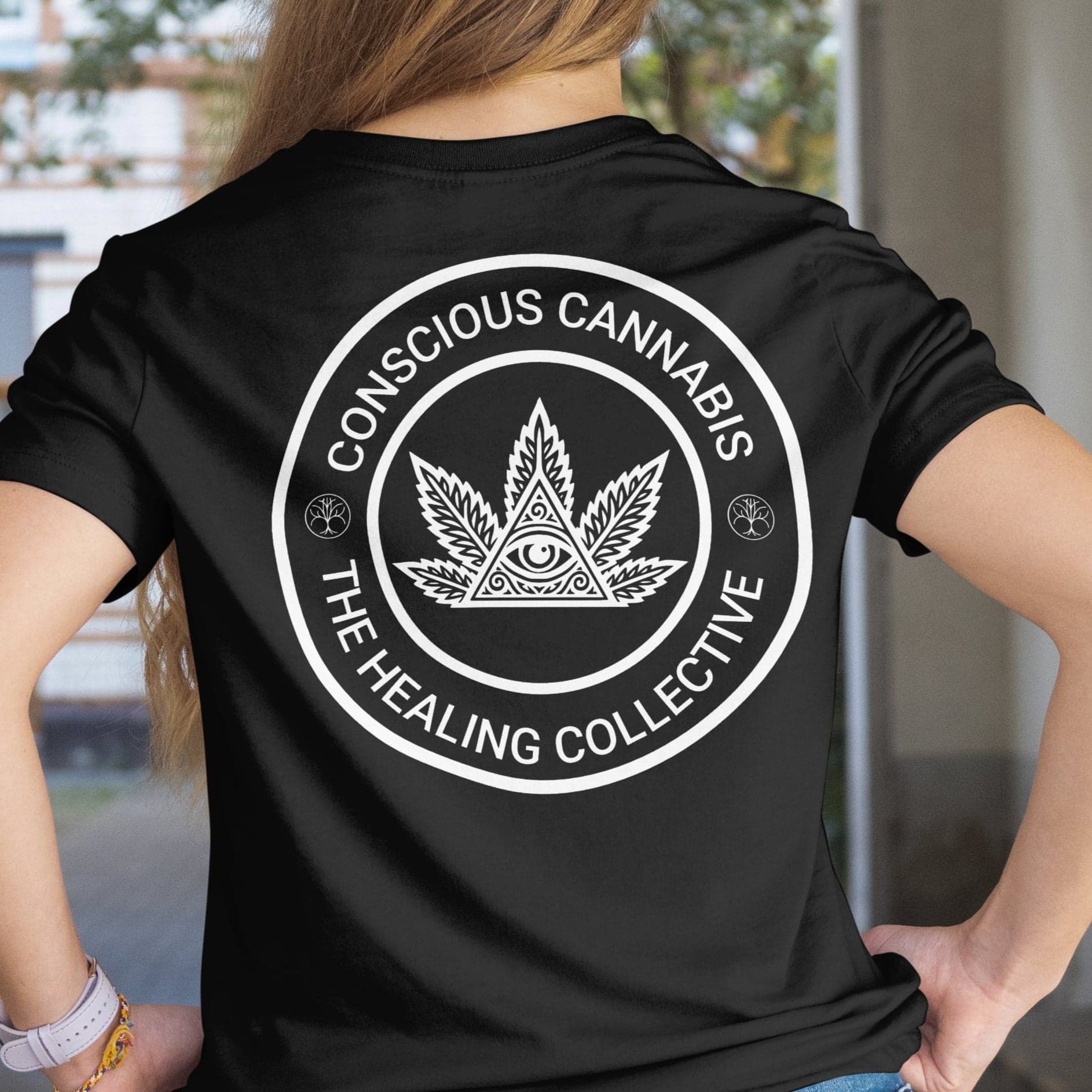 Person wearing a black t-shirt with 'Conscious Cannabis The Healing Collective' design on the back.
